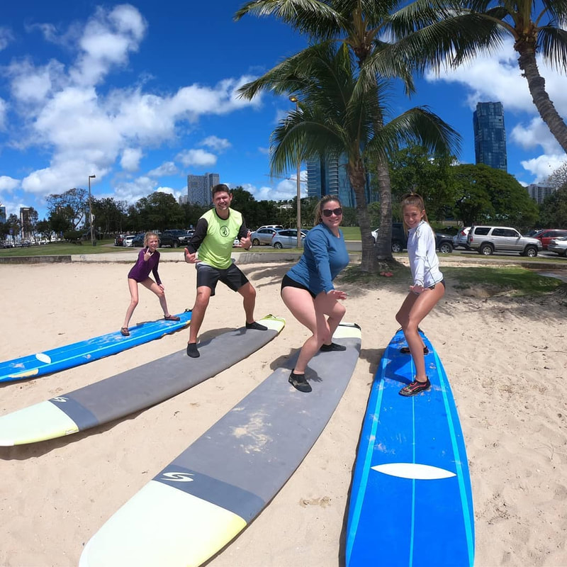 Family of 4 are practicing their form on the beach before surf session. Provided by Polu Lani Surf