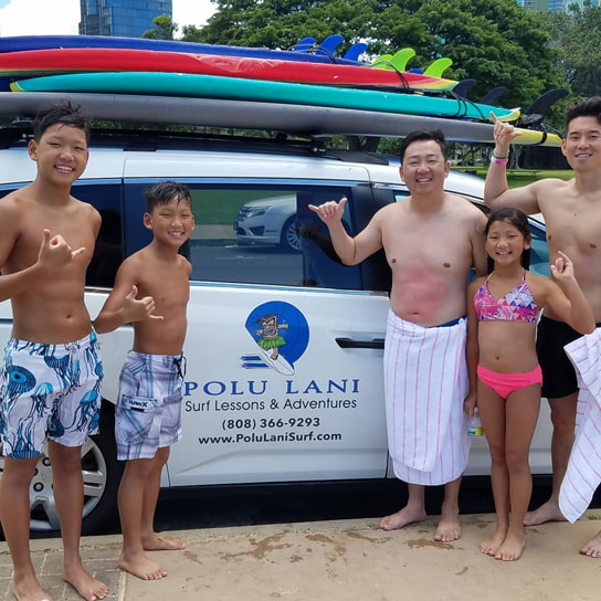 Family of 5 throwing shakas in front of the Polu Lani Surf van after a private surfing lesson. Provided by Polu Lani Surf