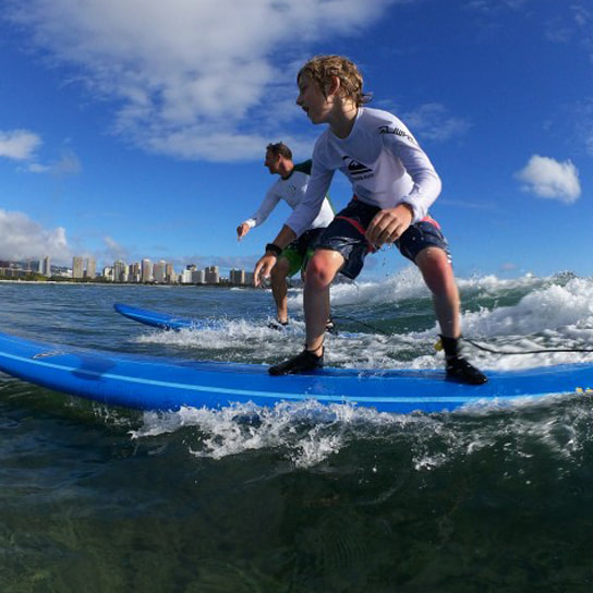 Photo of a father and son riding the same wave. Provided by Polu Lani Surf