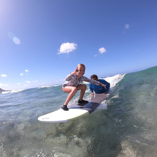 Instructor John and young girl catching a wave together. Provided by Polu Lani Surf