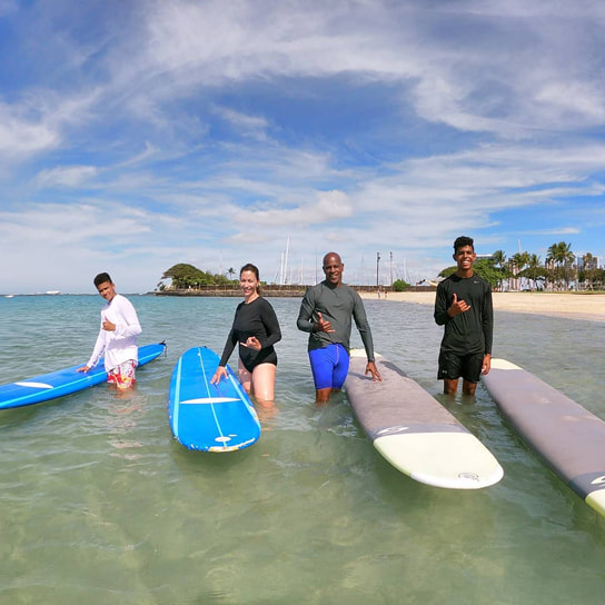 Family of 4 throwing shakas about to start their private surfing lesson. Provided by Polu Lani Surf